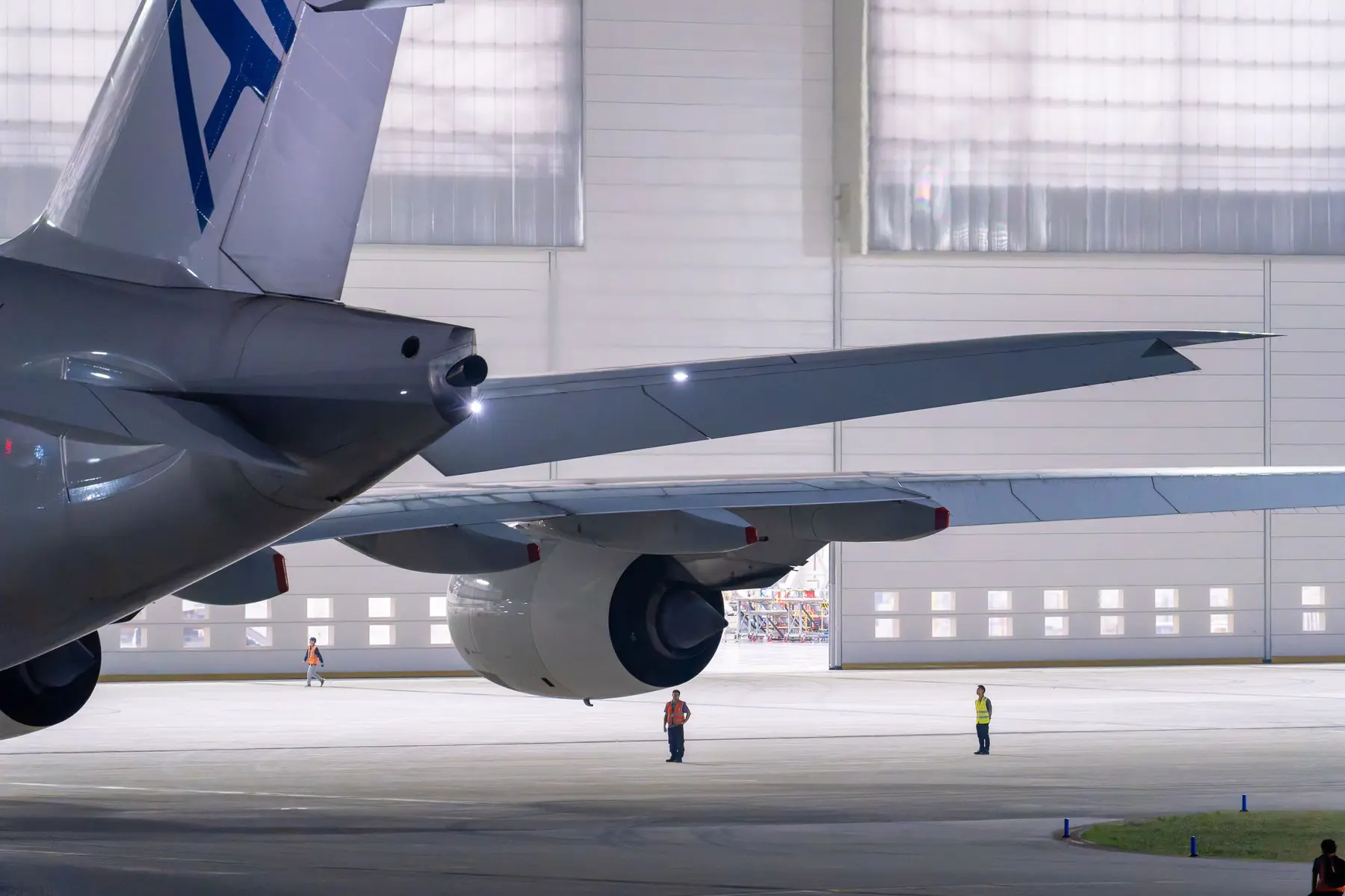 Commercial aircraft under maintenance in an illuminated hangar